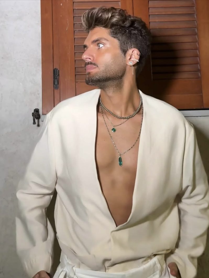 Man with a warm bronze tan in an open cream shirt